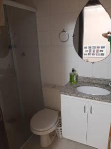 a bathroom with a toilet and a sink and a mirror at Sobrado confortável a uma quadra do mar. in Matinhos