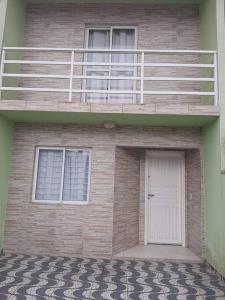 a building with a white door and a balcony at Sobrado confortável a uma quadra do mar. in Matinhos