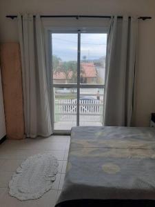 a bedroom with a bed and a large window at Sobrado confortável a uma quadra do mar. in Matinhos