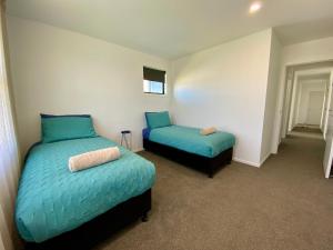 a bedroom with two beds with blue sheets and a window at Style, Functional with Space in Twizel