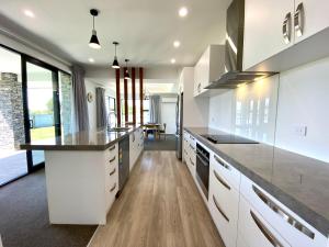 a large kitchen with white cabinets and a large island at Style, Functional with Space in Twizel