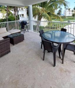 a patio with a table and chairs and a grill at Oceanfront Playa Turquesa with highspeed Wi-Fi, pools, free beach access in Punta Cana