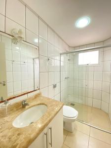 ein Badezimmer mit einem Waschbecken, einem WC und einem Spiegel in der Unterkunft Apartamento capão da canoa in Capão da Canoa