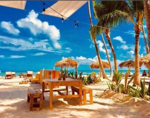 a picnic table and chairs on a beach with palm trees at Oceanfront Playa Turquesa with highspeed Wi-Fi, pools, free beach access in Punta Cana