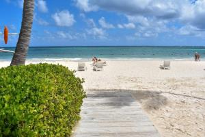 a beach with chairs and people in the water at Oceanfront Playa Turquesa with highspeed Wi-Fi, pools, free beach access in Punta Cana
