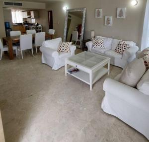a living room with white couches and a table at Oceanfront Playa Turquesa with highspeed Wi-Fi, pools, free beach access in Punta Cana
