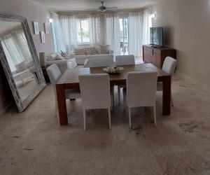 a dining room with a table and white chairs at Oceanfront Playa Turquesa with highspeed Wi-Fi, pools, free beach access in Punta Cana