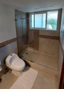 a bathroom with a toilet and a glass shower at Oceanfront Playa Turquesa with highspeed Wi-Fi, pools, free beach access in Punta Cana