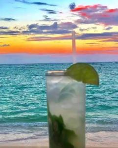 a drink with a lime slice in front of the ocean at Oceanfront Playa Turquesa with highspeed Wi-Fi, pools, free beach access in Punta Cana