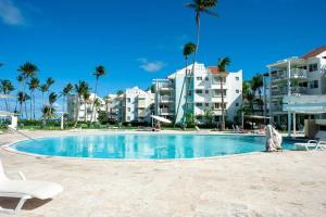 a swimming pool in a resort with palm trees and buildings at Oceanfront Playa Turquesa with highspeed Wi-Fi, pools, free beach access in Punta Cana