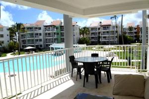 a balcony with a table and chairs next to a pool at Oceanfront Playa Turquesa with highspeed Wi-Fi, pools, free beach access in Punta Cana