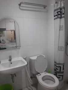 W łazience znajduje się toaleta, umywalka i lustro. w obiekcie Tamansari Mahogany Apartment By Sagita Residence Karawang w mieście Karawang