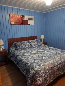 1 dormitorio con 1 cama con pared azul en Cabañas San Fernando en Futrono