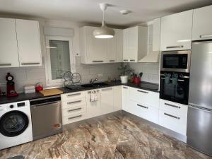 a kitchen with white cabinets and a washer and dryer at L' appart de Chantal in Lherm