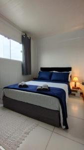 ein Schlafzimmer mit einem großen Bett mit blauer Bettwäsche und einem Fenster in der Unterkunft Celebre Cama e Café (B&B) in Florianópolis