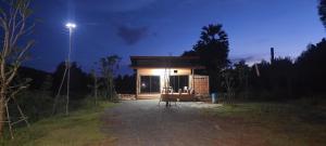 una pequeña casa con una luz encendida por la noche en ไร่ปายฉัตร โฮมสเตย์ สระแก้ว, en Ban Khanthung Noi