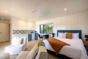 Onetangi Beach Stays Studio 2 - Coast & Country في Onetangi: غرفة نوم بسرير كبير ومطبخ