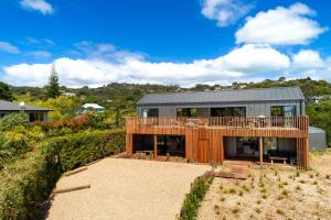 a house with a deck on top of a yard at Onetangi Beach Stays Studio 2 - Coast & Country in Onetangi