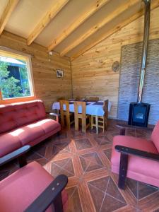 a living room with a couch and a tv and a table at CABAÑAS RUCA MALAL in Futrono