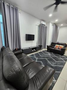 a living room with a leather couch and a flat screen tv at MIHI Homestay Pantai Sepat in Kuantan