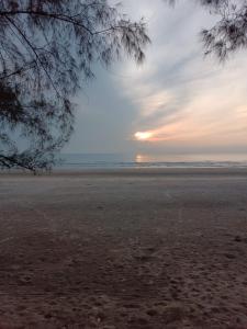 einen Strand mit Sonnenuntergang in der Ferne in der Unterkunft MIHI Homestay Pantai Sepat in Kuantan