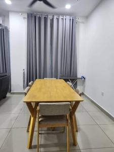 einen Holztisch und Stühle in einem Zimmer mit Vorhängen in der Unterkunft MIHI Homestay Pantai Sepat in Kuantan