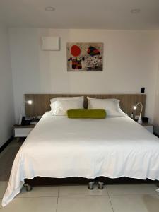 1 dormitorio con cama blanca grande y almohada verde en Towers Confort, en Rionegro