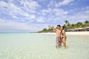 a man and a woman standing in the water on a beach at Paradise Garden Hotel and Convention Boracay Powered by ASTON in Boracay