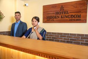 Um homem e uma mulher atrás de um balcão. em Hotel Hidden Kingdom em Pokhara
