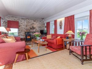 uma sala de estar com mobiliário vermelho e uma parede de pedra em Druidston Old Farmhouse em Nolton