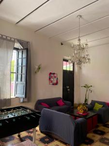 a living room with couches and a table and a chandelier at Hostal Rosa Mexicano in Mérida