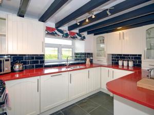 a kitchen with white cabinets and red counter tops at South Nolton Farmhouse-qc1265 in Nolton