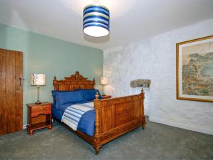 a bedroom with a wooden bed with blue sheets at South Nolton Farmhouse-qc1265 in Nolton