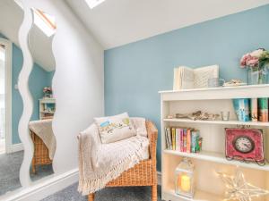 a room with a chair and a book shelf at Daffodil Cottage in Laugharne