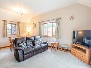 a living room with a leather couch and a flat screen tv at Oak Cottage - Uk45576 in Maltby le Marsh