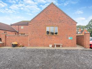 a brick building with a window and a bench at Oak Cottage - Uk45576 in Maltby le Marsh