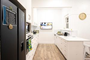 a kitchen with white cabinets and a black refrigerator at Fairleys of Corowa in Corowa