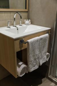 a bathroom with a sink with towels under it at Fuente Mayor Hotel Terminal in Mendoza