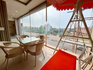 d'un balcon avec une table, des chaises et une grande fenêtre. dans l'établissement The Starlet Prime, A Hidden Peaceful Stay, à Chandigarh