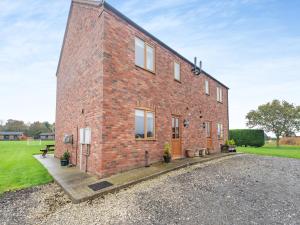 a red brick building with windows on a field at Lake View 1 - Uk45577 in Maltby le Marsh