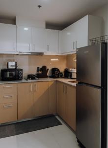 a kitchen with white cabinets and a black refrigerator at Uptown Parksuites 1BR with Wi-Fi, Free Netflix, Washer & Pool View in Manila