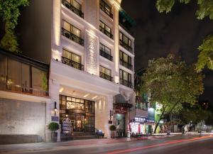 a tall white building on a city street at night at GM Premium Hotel in Hanoi