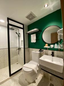 a bathroom with a toilet and a sink and a mirror at Alltrue Hotel Bintan - Tanjungpinang in Tanjung Pinang 
