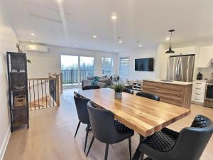a kitchen and living room with a wooden table and chairs at Le domaine du Sous-Bois in Mont-Blanc