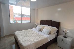Santa Rosa de Viterbo的住宿－Moderno Apartamento Central，一间卧室配有一张带白色床单的床和一扇窗户。
