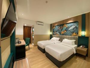 a hotel room with two beds and a television at Alltrue Hotel Bintan - Tanjungpinang in Tanjung Pinang