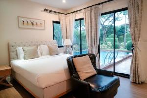 a bedroom with a bed and a chair in front of a window at Chivani Pattaya in Na Jomtien