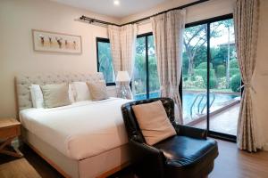 a bedroom with a bed and a chair in front of a window at Estella Pool Villas Pattaya Formerly Chivani Pattaya in Na Jomtien +74 photos