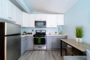 a kitchen with white cabinets and a refrigerator and a table at Cozy 1 BR in Historic SD Walk to Restaurants in San Diego