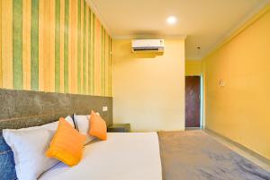 Swastic Hotel at Calangute GOA في كالانغيُت: غرفة نوم مع سرير مع وسائد برتقالية وبيضاء